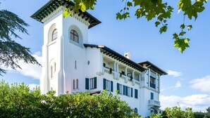 A white building with a tower, balconies, and a clear sky.