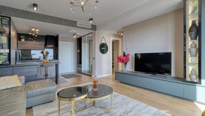 Een moderne woonkamer met een bank, een televisie, een eethoek en een keuken.