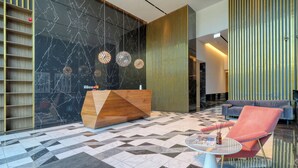 Een moderne lobby met een receptiebalie, een zithoek en een vloer met een patroon.