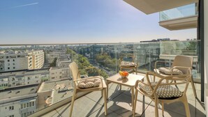 Een balkon met twee stoelen en een tafel, met uitzicht op een stadsbeeld.