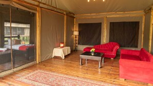 Une pièce aménagée avec une tente, un lit, un canapé rouge, une petite table et une lampe.