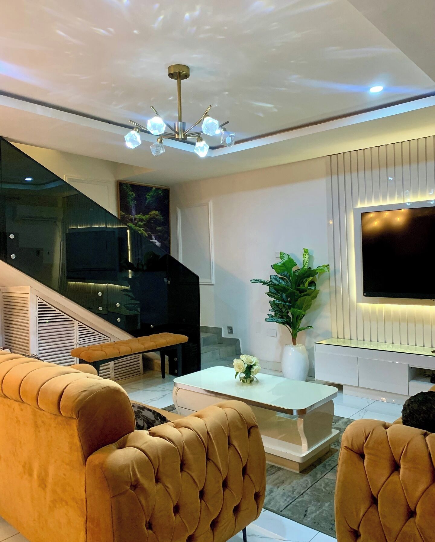 Una sala moderna con un sofá, una mesa de centro, un televisor y una escalera.