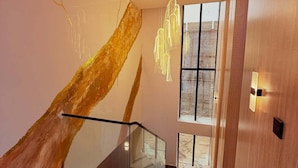 Een moderne trap met glazen balustrades, een houten accentmuur en een hangende lamp.