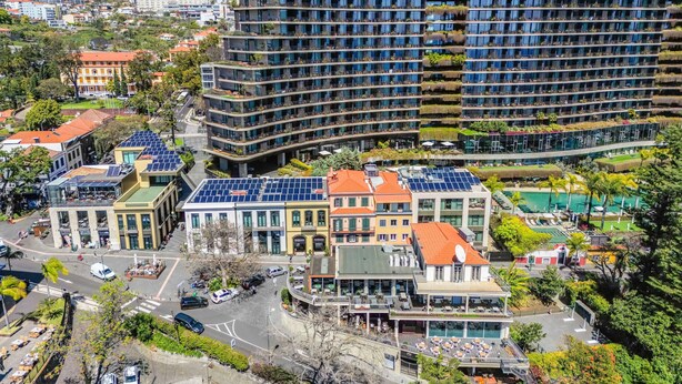 Un hotel de varios pisos con balcones, paneles solares y una zona de piscina.