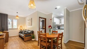 Una sala de estar moderna con una mesa de comedor de madera, un sofá y una cocina al fondo.