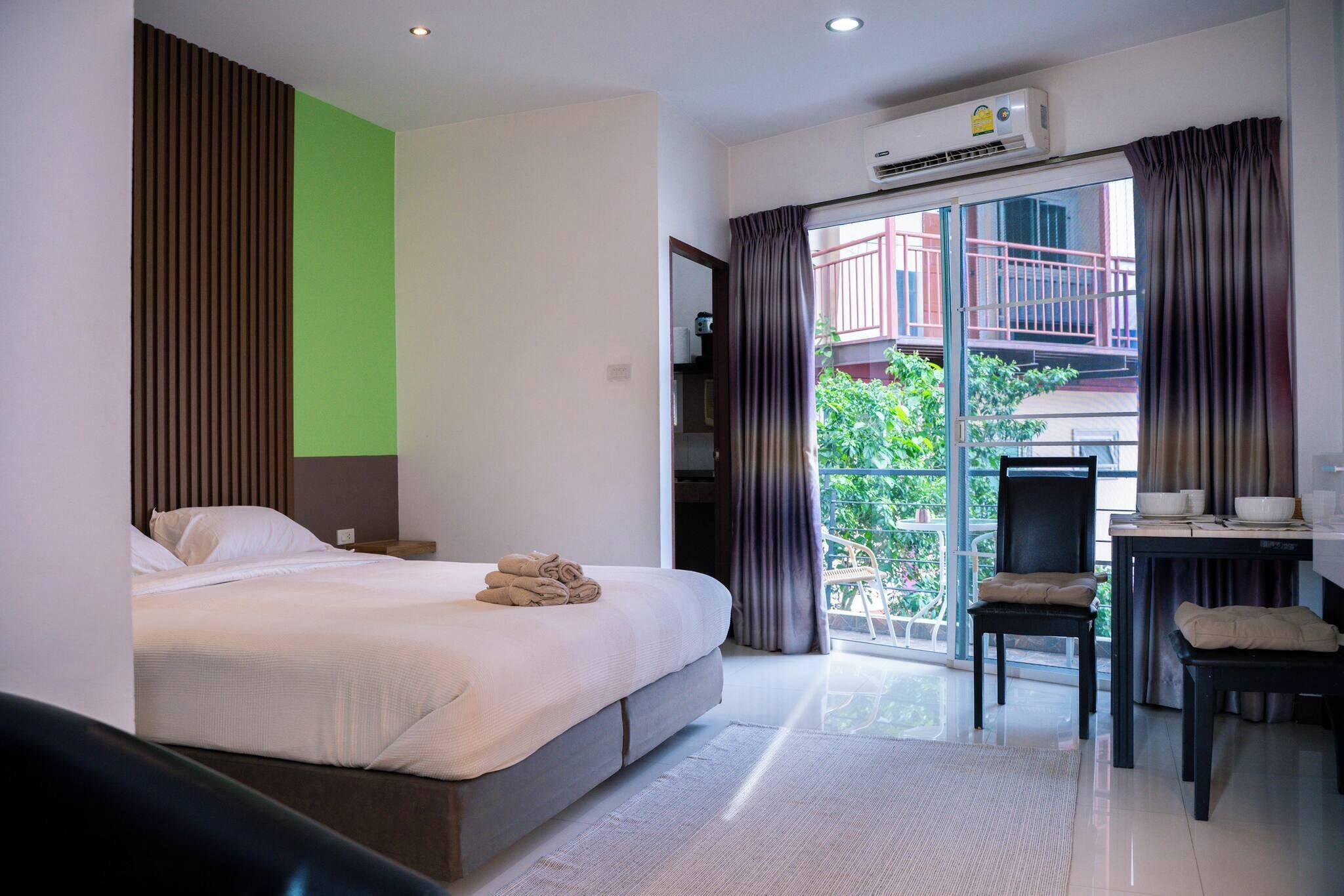 Ein modernes Hotelzimmer mit Bett, Schreibtisch und einem Balkon mit Vorhängen.