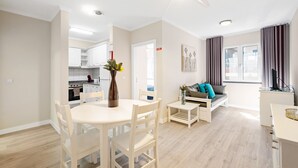 Ein modernes Wohnzimmer mit Essbereich, einer Couch und einer Küche im Hintergrund.