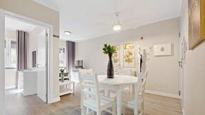 Ein modernes Hotelzimmer mit Essbereich, Deckenventilator, Blumenvase und einem Bild an der Wand.