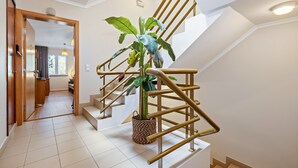 Eine Treppe mit Pflanze, eine Holztür und ein Flur, der zu einem Zimmer führt.