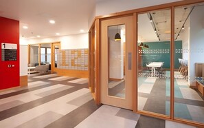 A modern office space with a meeting room, a reception area, and a glass partition.