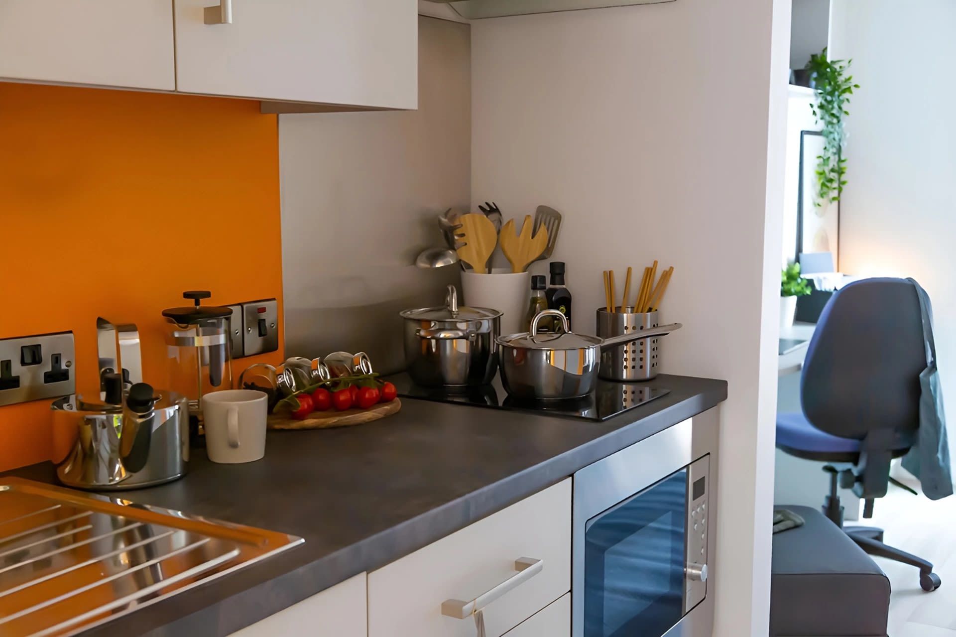 Una cocina moderna con electrodomésticos de acero inoxidable, cafetera y diversos utensilios.