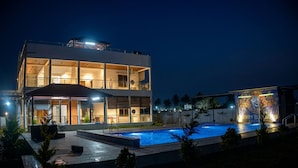 Ein modernes Hotel mit Pool, Außenbereich und einer gut beleuchteten Fassade.
