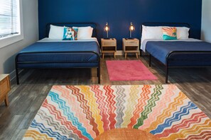 Bedroom with two beds, a navy accent wall, and a colorful sunburst area rug. - | The Funky Mermaid at East Bay Inn Pet Friendly (Panama City)