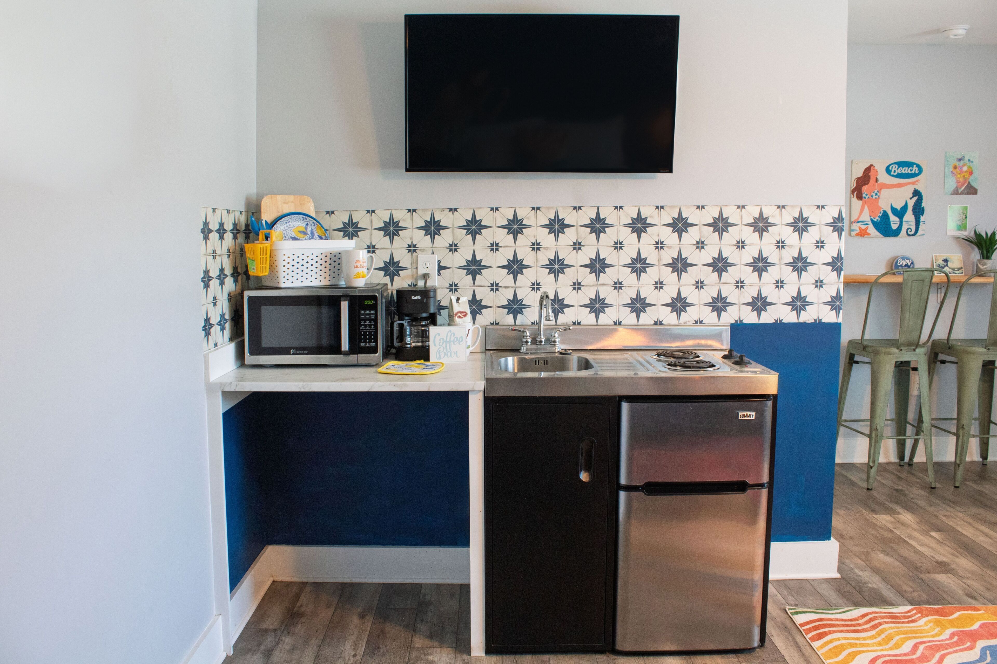 A compact kitchenette setup featuring an all-in-one unit and wall-mounted TV.
