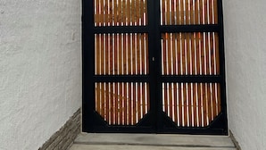 A black gate with vertical slats, a concrete floor, and a wooden beam structure above. - Zerilith Haven self catering (Swakopmund)