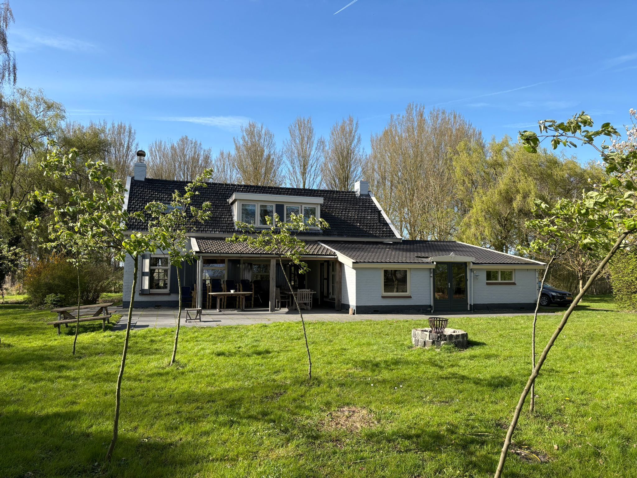 Ein zweistöckiges Haus mit einer überdachten Terrasse, einem Rasen und Bäumen im Hintergrund.