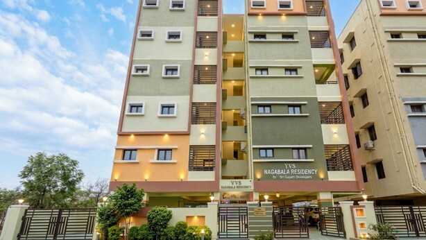 Ein mehrstöckiges Gebäude mit Balkonen, mit der Aufschrift 'Oasis Luxury Guestrooms' und 'Nagabala Residency'.