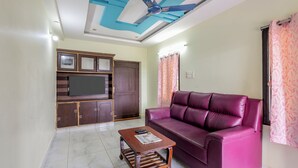 Ein Wohnzimmer mit Sofa, Couchtisch, Fernseher und Deckenventilator.