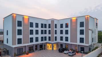 A multi-story hotel with a central courtyard, large windows, and a parking area.