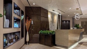 A modern reception area with a curved reception desk, wall-mounted art, and a decorative vase with dried plants.