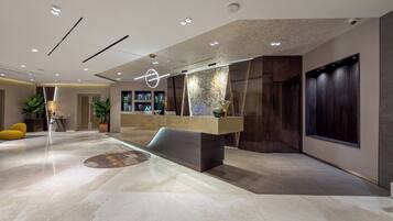 A modern lobby with a reception desk, seating area, and decorative elements.