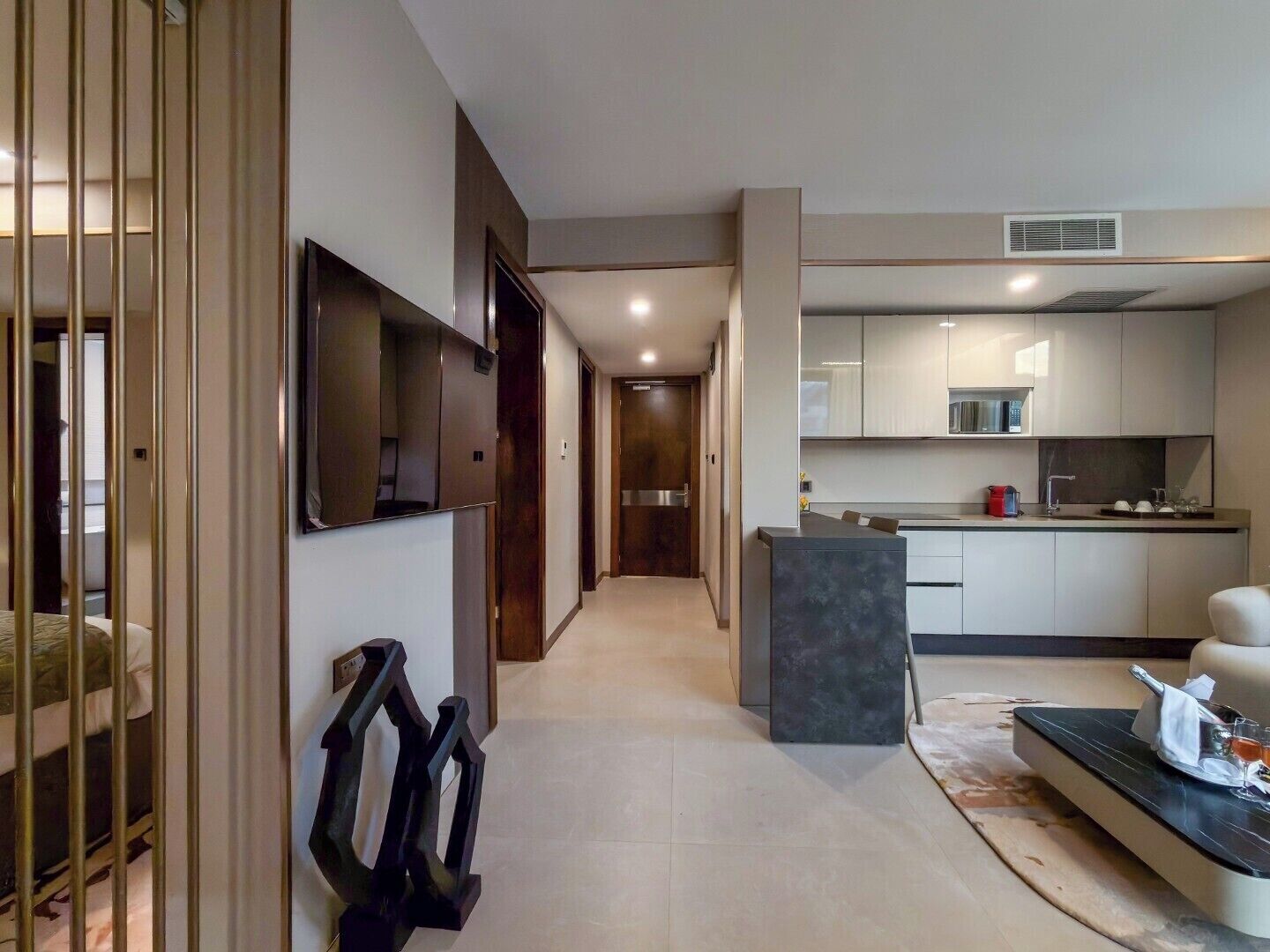 Una habitación de hotel moderna con sala de estar, cocina y pasillo.