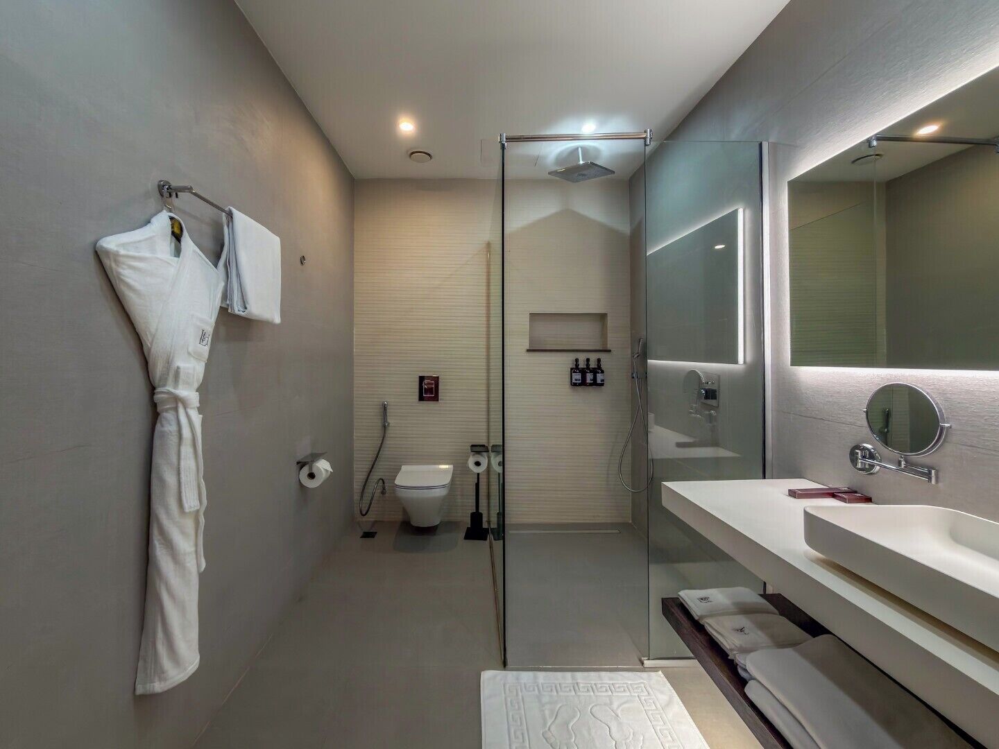 A modern bathroom with a glass shower enclosure, a large mirror, and a white bathtub.