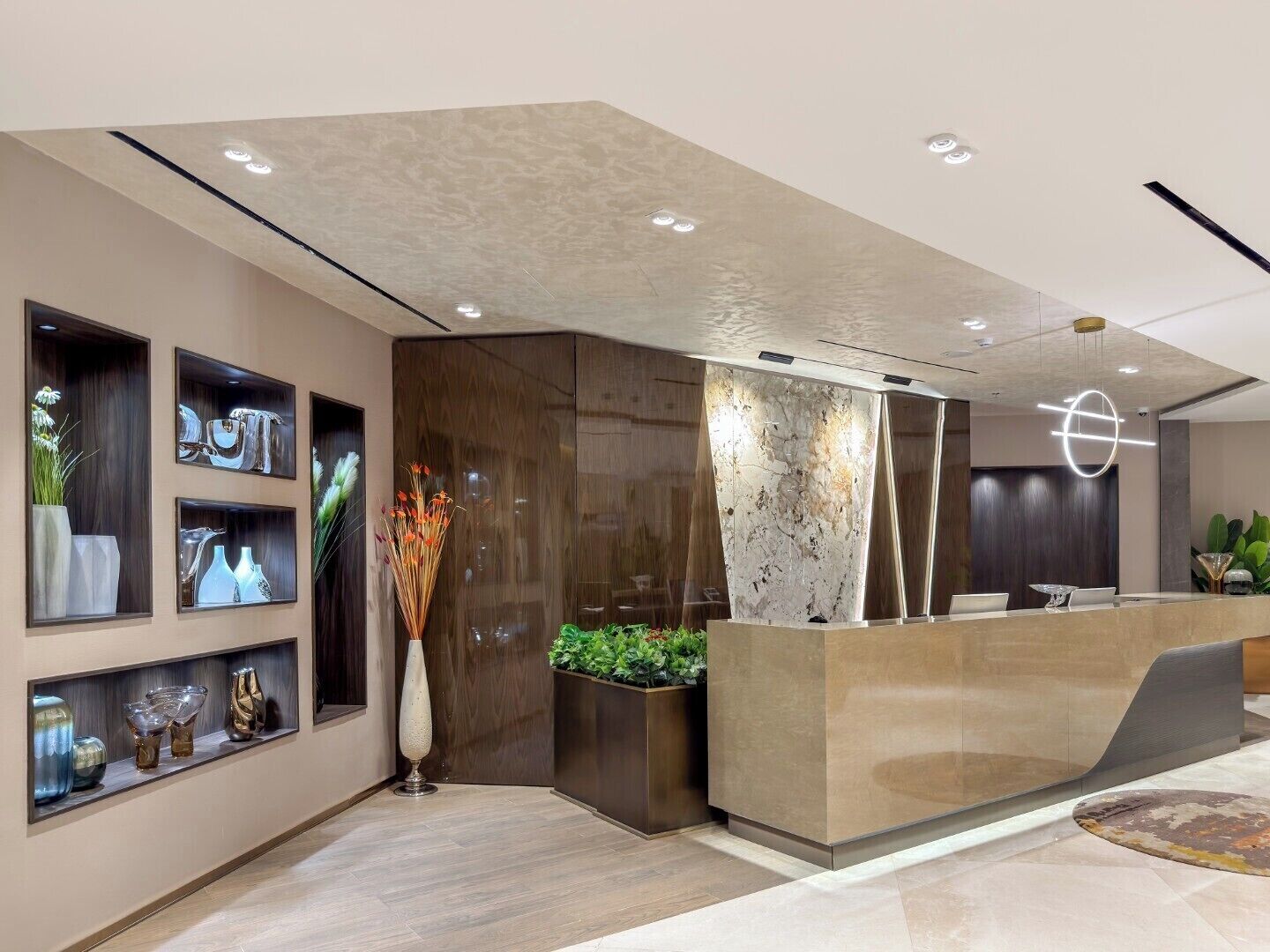 Una zona de recepción moderna con un mostrador de mármol, estanterías empotradas con objetos decorativos y un diseño minimalista.