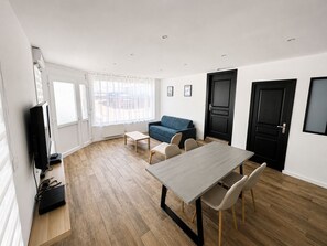 A modern living room with a sofa, a dining table, and a TV. - Le cocon Portelois (Le Portel)