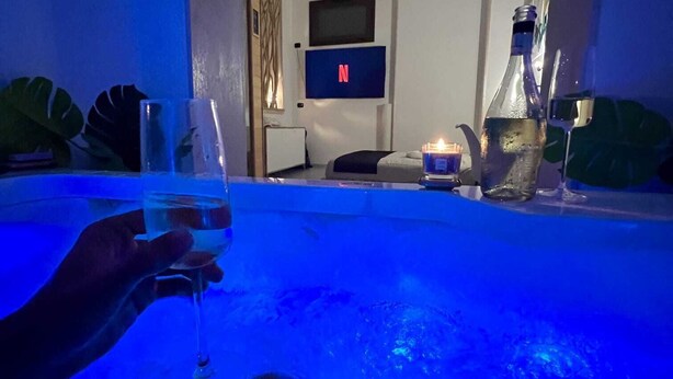 A person relaxing in a hot tub with a TV in the background. - House with hot tub ( BRAMA WELLNESS EXPERIENCE) (Brindisi)