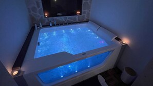 A hot tub with a stone wall backdrop and a mounted television. - House with hot tub ( BRAMA WELLNESS EXPERIENCE) (Brindisi)