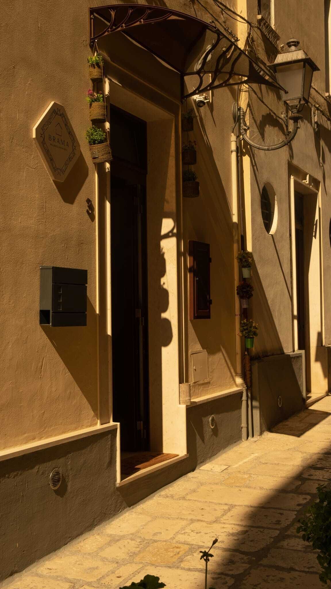 Un carrer estret amb edificis, una porta i plantes penjants.