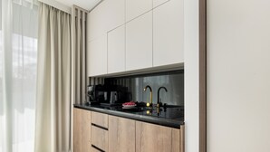 A modern kitchen with a black countertop, wooden cabinets, a coffee maker, and a sink. - Bluewave - Wave Resort & Spa (Międzyzdroje)