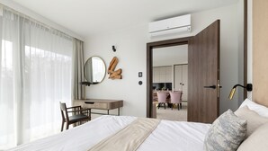 A hotel room with a bed, a desk, a chair, a mirror, a door, and an air conditioning unit. - Bluewave - Wave Resort & Spa (Międzyzdroje)