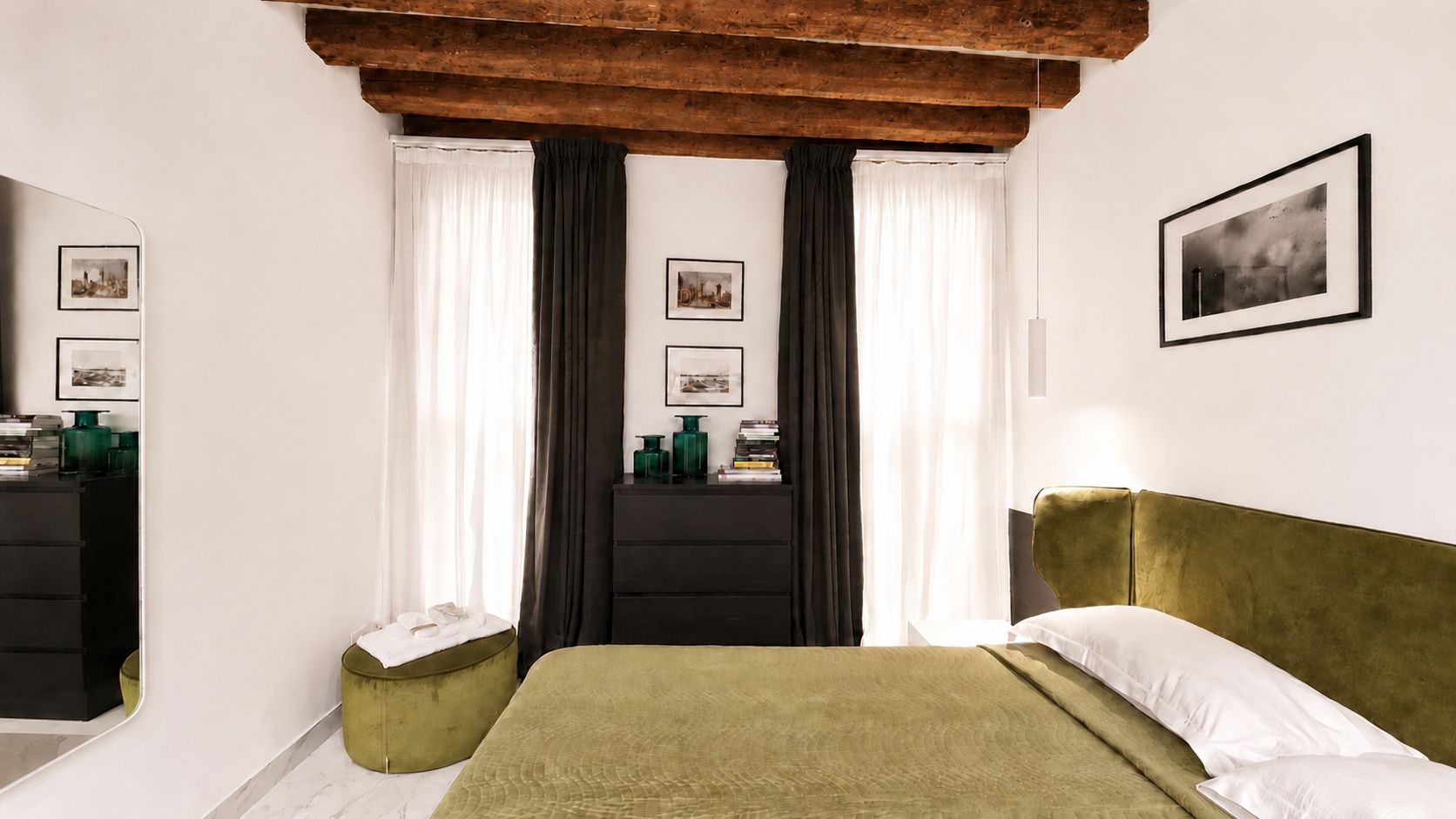 A bedroom with a bed, a dresser, a nightstand, and a window with curtains.