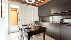 Eine moderne Küche mit dunklen Schränken, einem eingebauten Backofen und einem Essbereich mit Holztisch und weißen Stühlen.