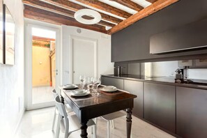 Eine moderne Küche mit dunklen Schränken, einem eingebauten Backofen und einem Essbereich mit Holztisch und weißen Stühlen.