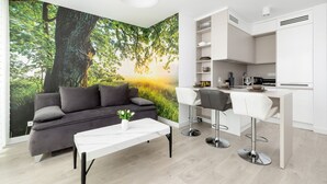 A modern living room with a sofa, a white coffee table, and a kitchen area with a bar. - Nubo - Wave Resort & Spa (Międzyzdroje)
