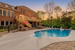 A brick house with a pool, outdoor seating, and a deck.