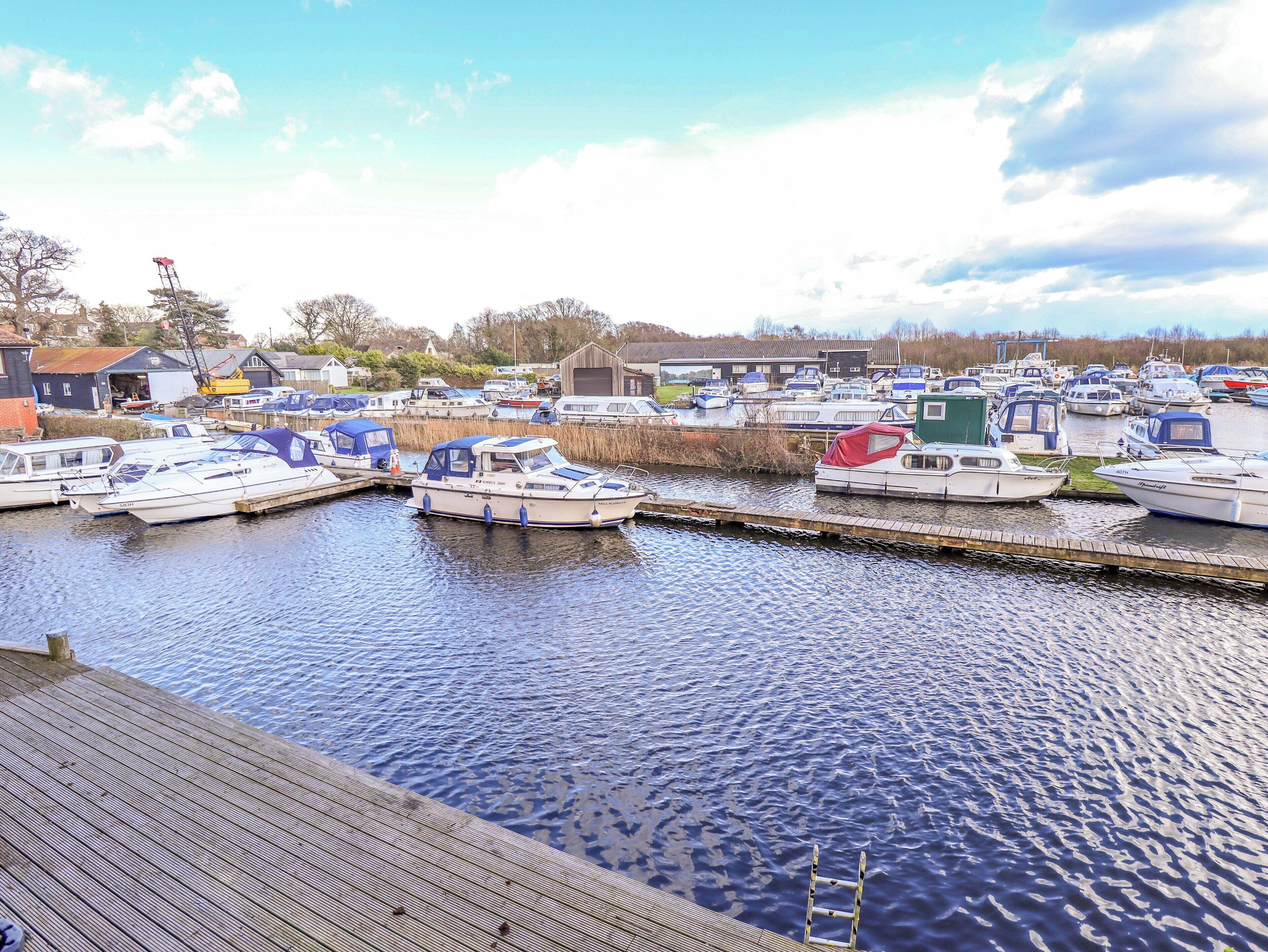 A marina with various boats docked, a wooden dock, and a clear sky.