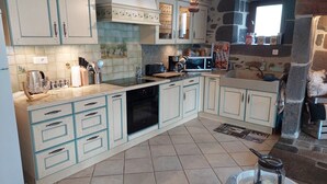 A kitchen with white cabinets, a black oven, a microwave, and a coffee maker. - Charming 6-person house with large terrace - near Salers and Puy Mary (Anglards-de-Salers)