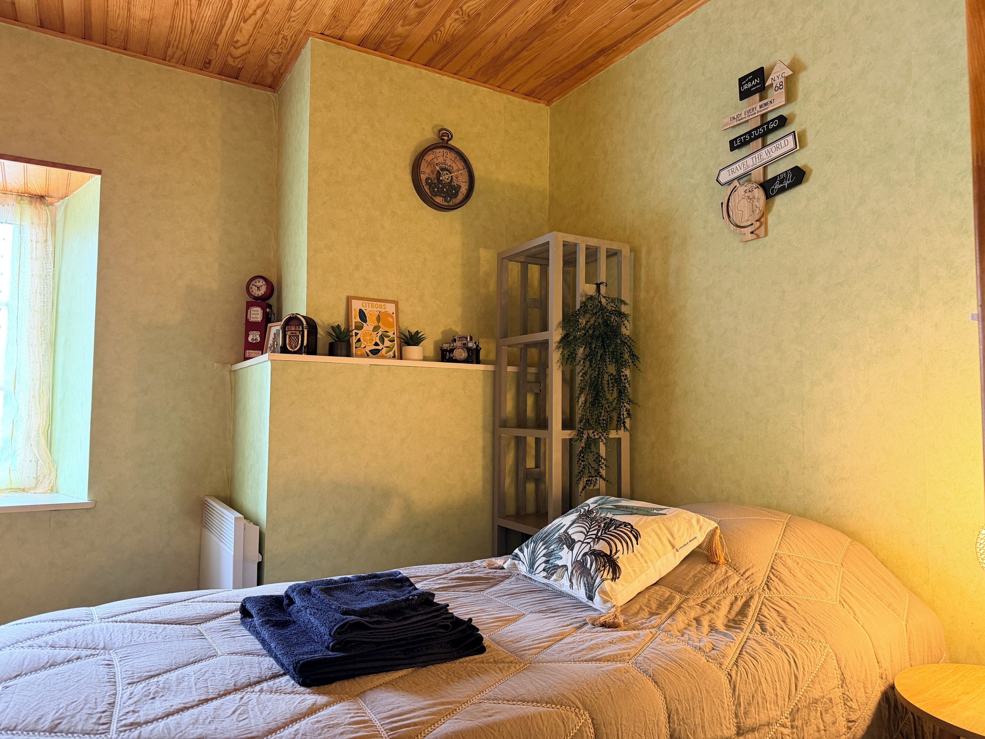 Un dormitorio con cama, una estantería con adornos, un reloj y una ventana.