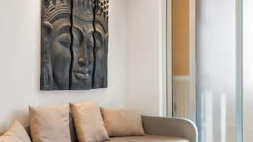 Un salon moderne avec un canapé, des coussins et une grande sculpture en pierre accrochée au mur.