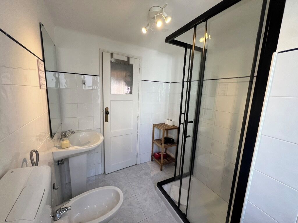 A modern bathroom with a glass shower enclosure, a sink, and a toilet.