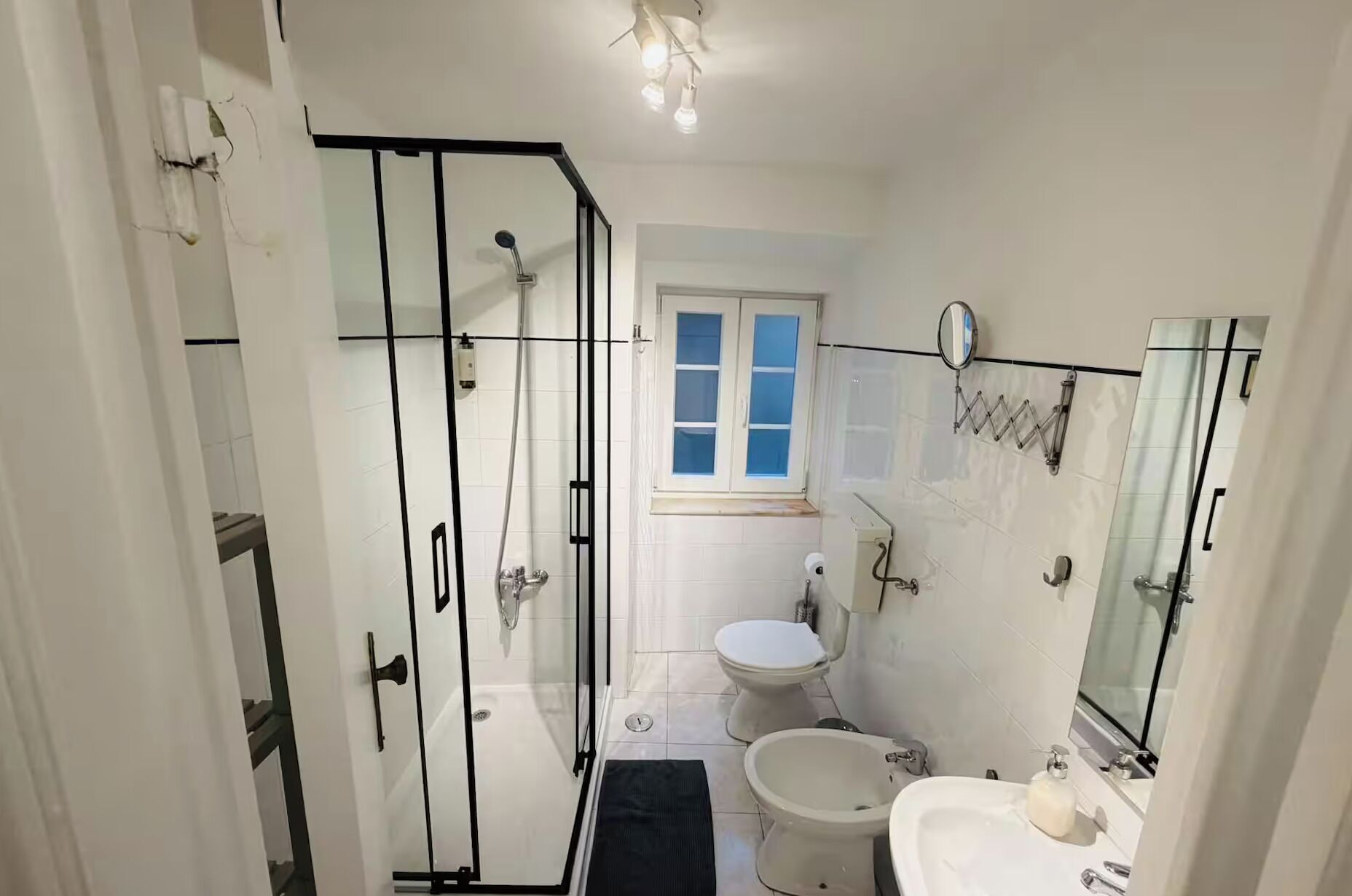 A bathroom with a glass shower enclosure, a toilet, a bidet, and a sink with a mirror.