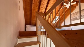 A wooden staircase with a handrail, leading to a room with a ceiling fan and a window. - Modern vacation apartment on Lake Constance in Lindau with balcony (Lindau (Bodensee))
