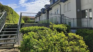 A residential building with multiple balconies, a staircase, and lush greenery. - Modern vacation apartment on Lake Constance in Lindau with balcony (Lindau (Bodensee))