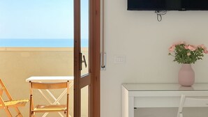 A balcony with a table and chairs, a television mounted on the wall, and a vase with flowers on a table. - PSE03 - Porto Sant'Elpidio, sea front charming two-room apartment (San Tommaso Tre Archi, Fermo)
