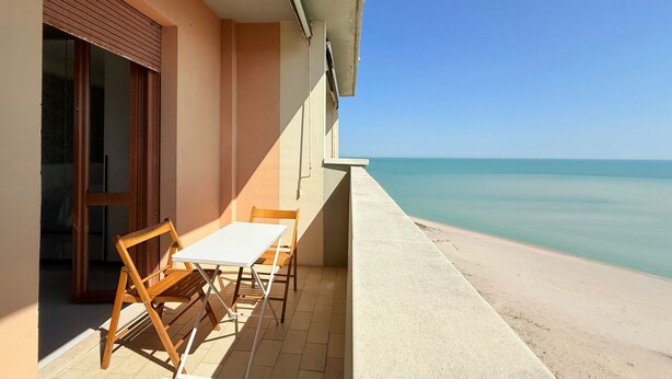 A balcony with a table and chairs, a sliding glass door, and a view of the sea. - PSE03 - Porto Sant'Elpidio, sea front charming two-room apartment (San Tommaso Tre Archi, Fermo)