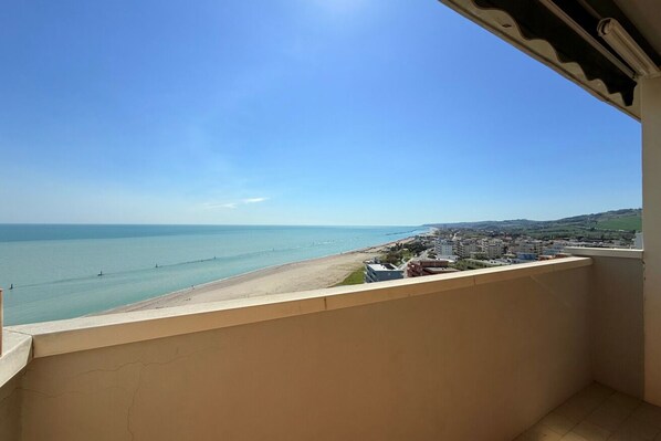 A balcony with a view of a beach and cityscape.
